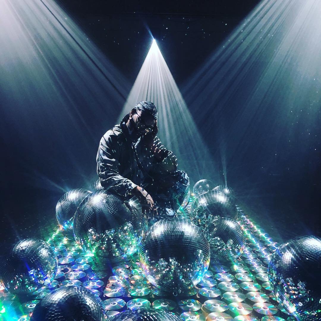 The photo shows a large room filled with CDs, mirror balls, and projection mapping creating a room filled with shimmering mirror reflections that look like the night sky.