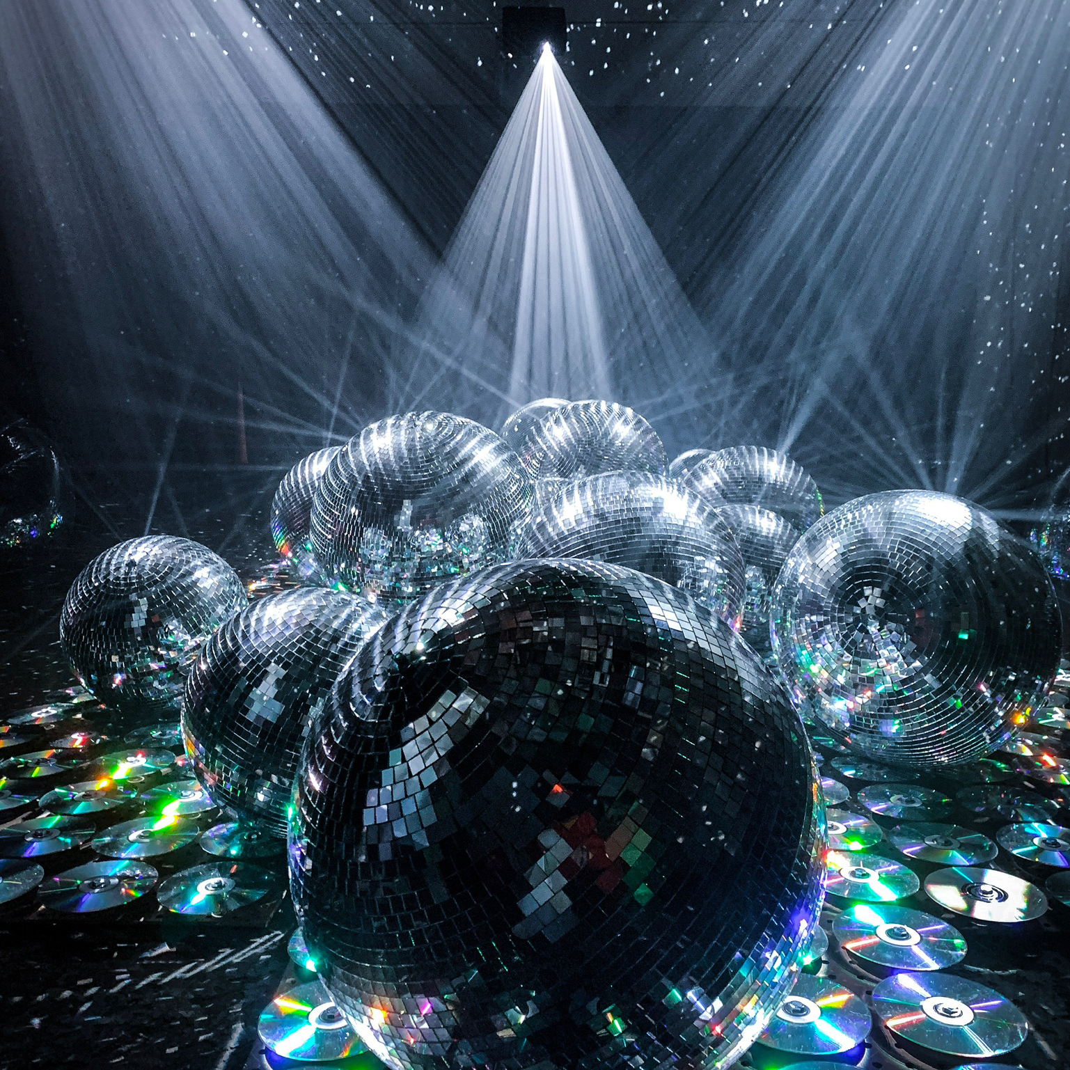 The photo shows a large room filled with CDs, mirror balls, and projection mapping creating a room filled with shimmering mirror reflections that look like the night sky.