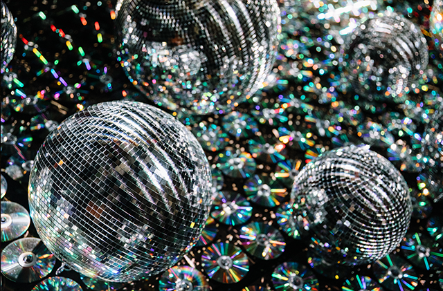 The photo shows a close up on CDs, mirror balls, and projection mapping creating a room filled with shimmering mirror reflections that look like the night sky.
