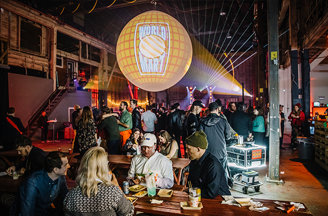 A photo of the End of the World Mart, a magical, immersive environment that combines nostalgia for the '90s and the early 2000s with futuristic elements. There is a massive 4-meter projection-mapped sphere in the center of the room with people sitting all around it.